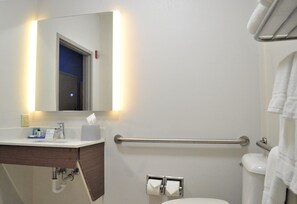 A bathroom with a white sink, mirror, and toilet. There is a towel rack on the wall and a handrail for accessibility. - Holiday Inn Express & Suites Batesville by IHG (Batesville)