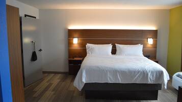 A hotel room with a large bed, bedside tables, a wardrobe, and a wall-mounted light fixture.