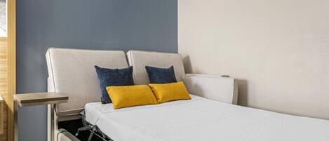 A compact bed with a headboard, two pillows, a bedside table, and a built-in storage unit.
