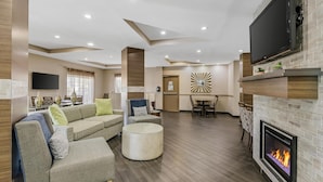 A modern living room with a fireplace, a flat-screen TV, and a dining area.