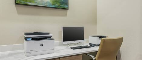 A modern office desk with an HP printer, a monitor, and a keyboard.
