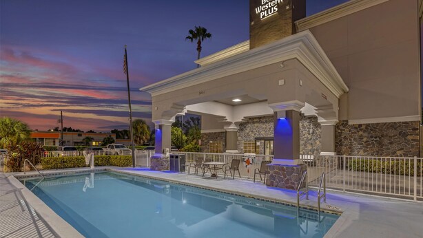 A pool area with a covered seating area, stone walls, and an American flag.