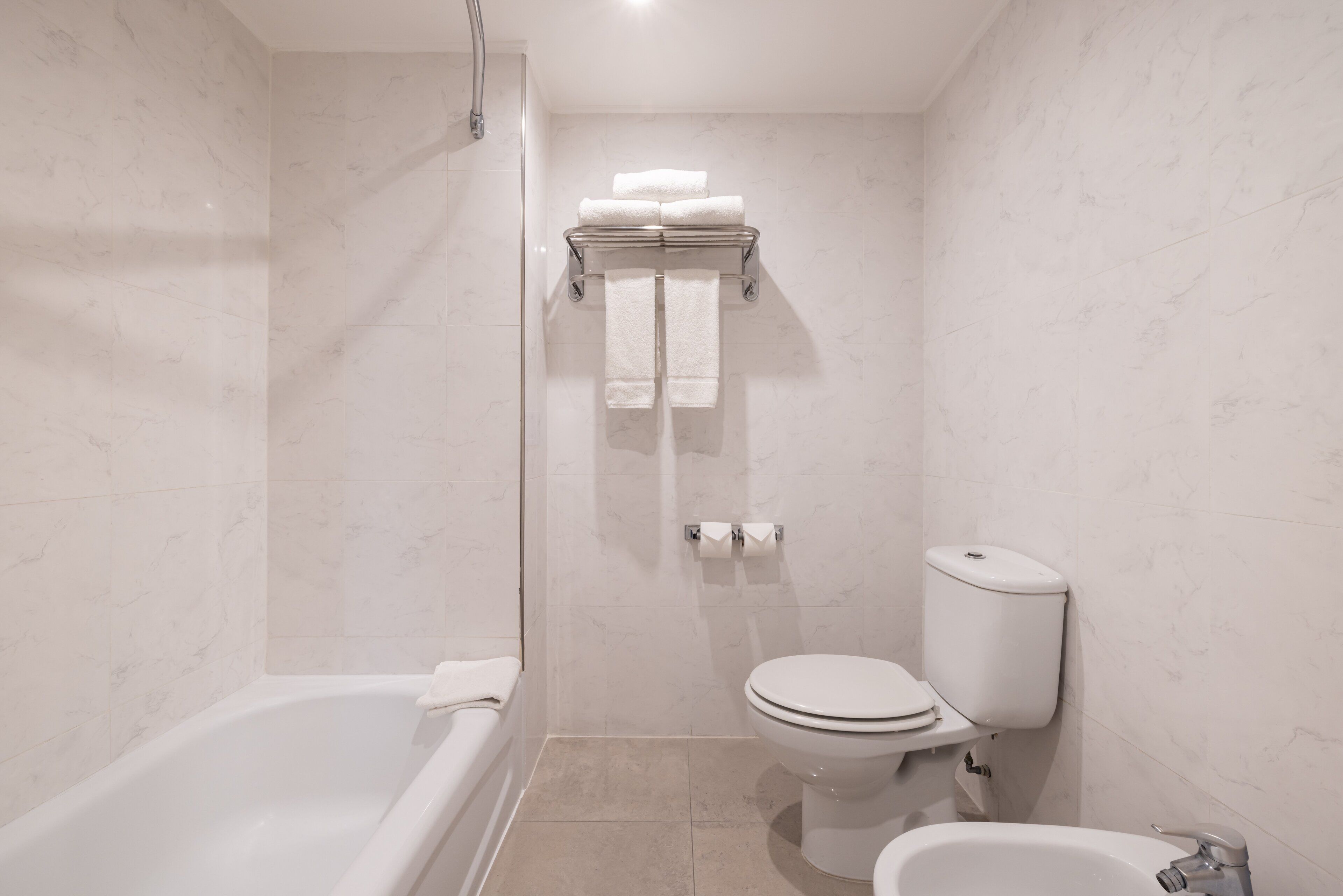 A modern bathroom with a bathtub, toilet, and bidet.
