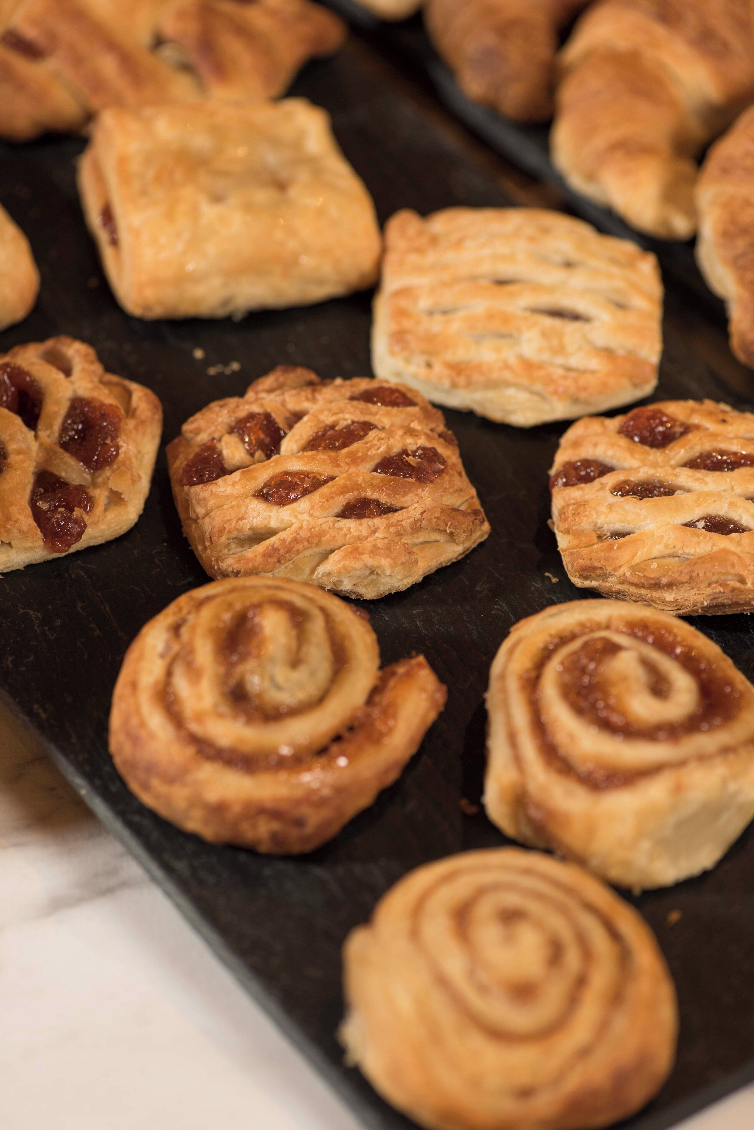 A tray of pastries with various shapes and a dark surface.