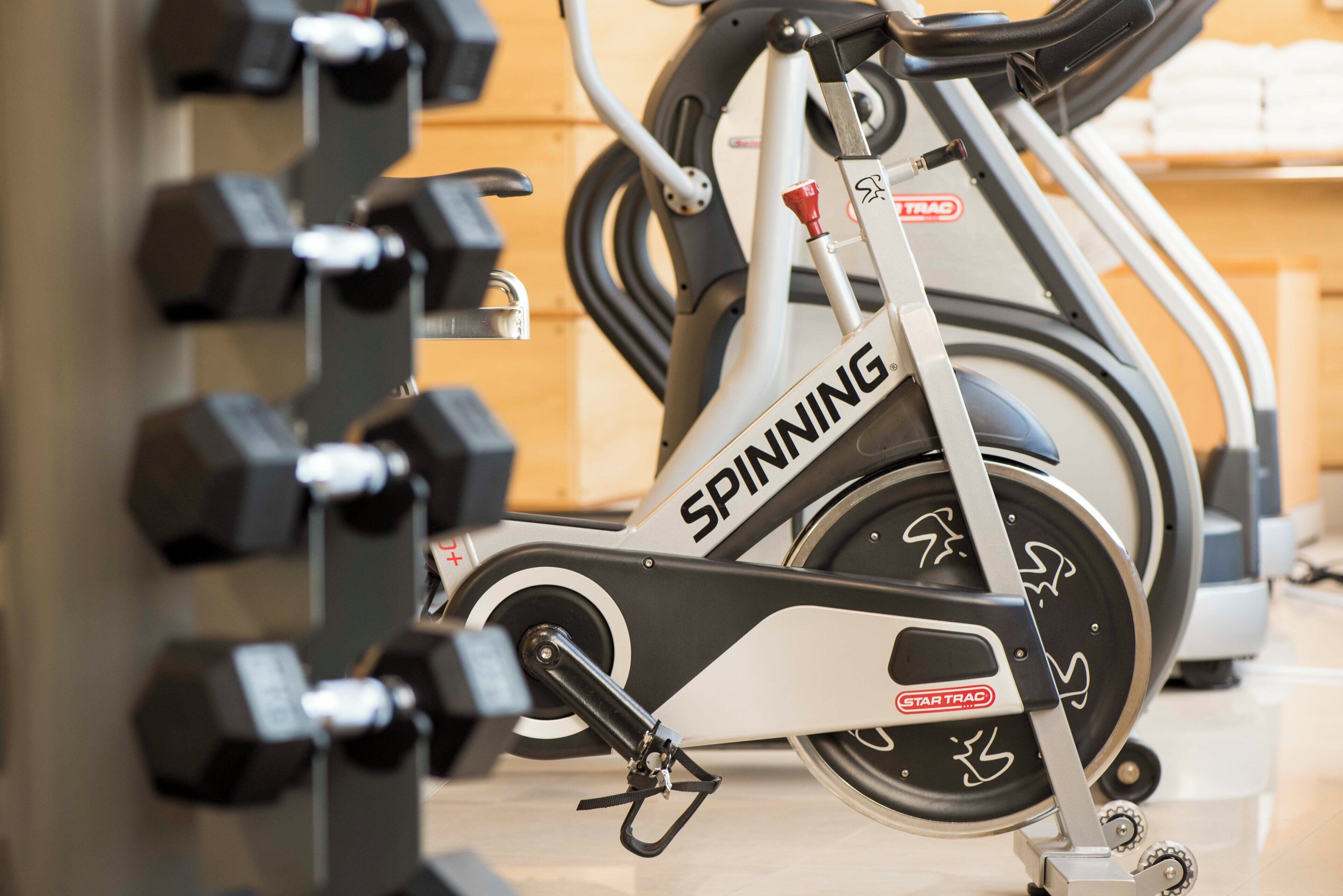 Una cyclette in palestra, con un supporto a parete per manubri.