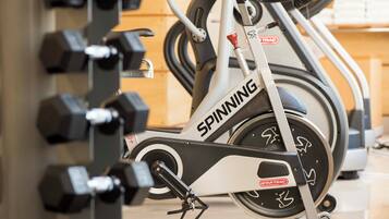 Una cyclette in palestra, con un supporto a parete per manubri.