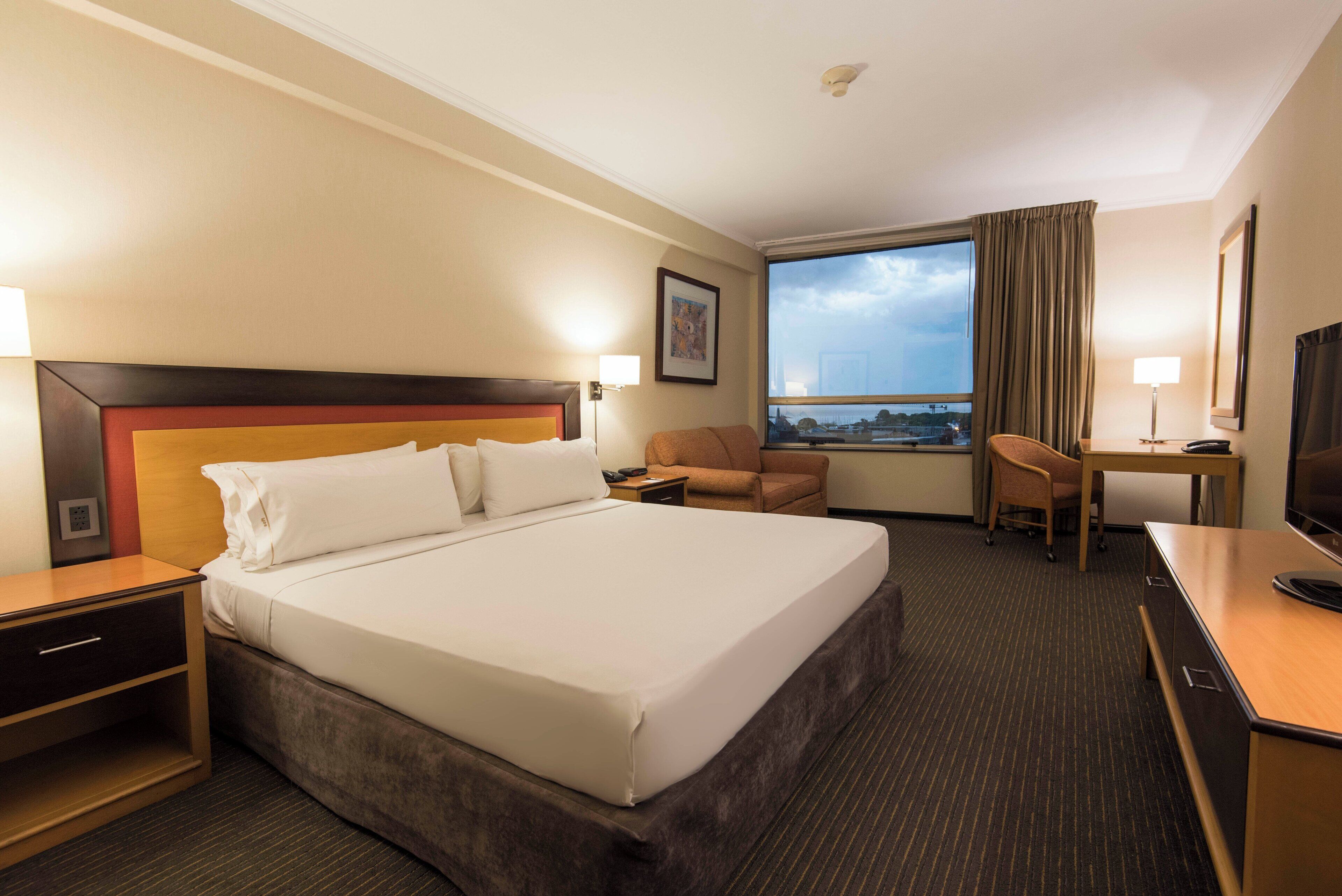 Een hotelkamer met een groot bed, een bureau, een stoel en een televisietoestel.