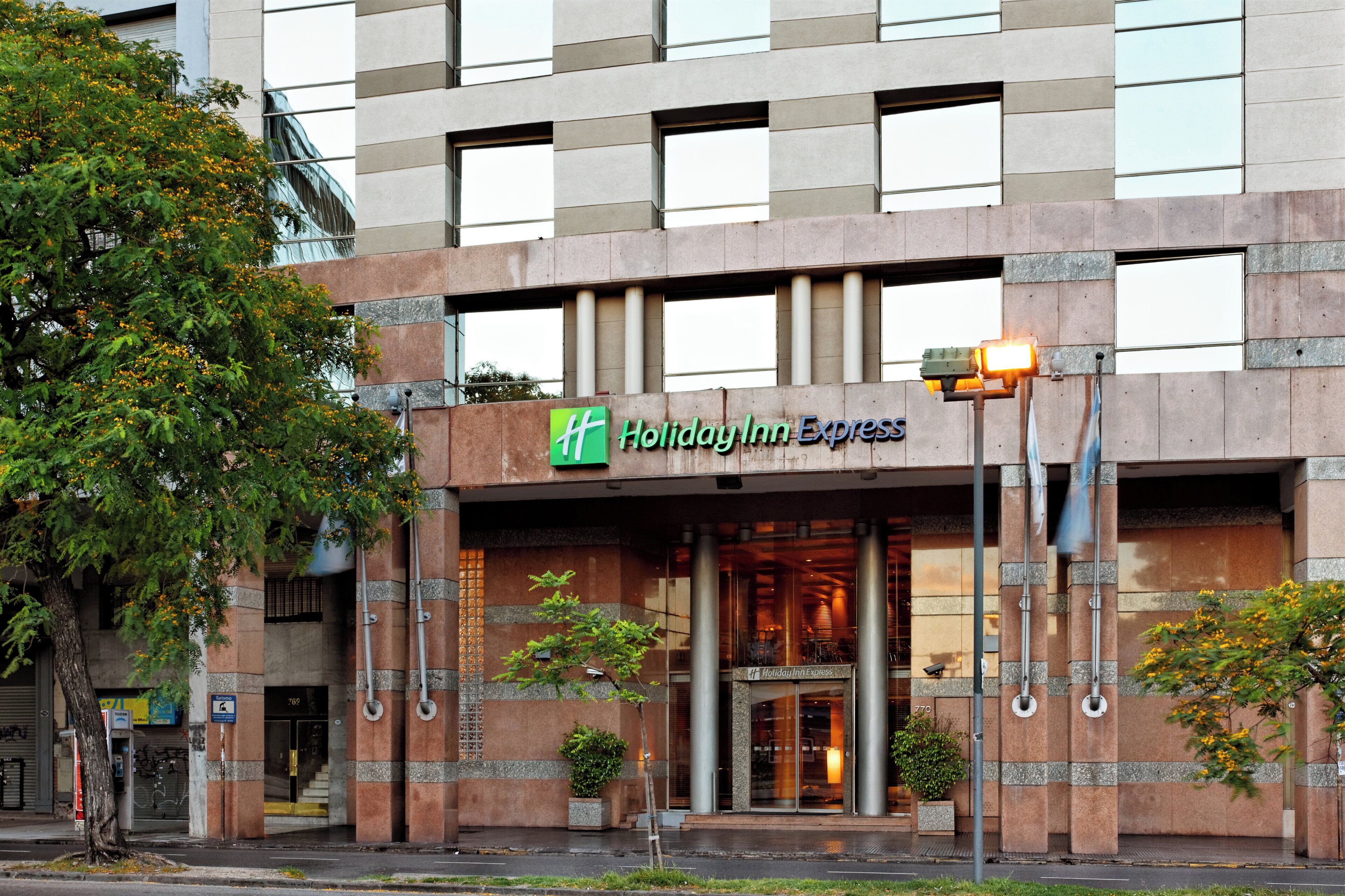 A Holiday Inn Express hotel entrance with a modern facade, large windows, and a visible entrance door.
