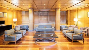 Un hall espacioso con diseño moderno, que incluye un sofá central, varios sillones y una mesa de centro.