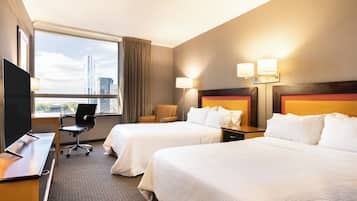 A hotel room with two beds, a desk, a chair, and a TV.