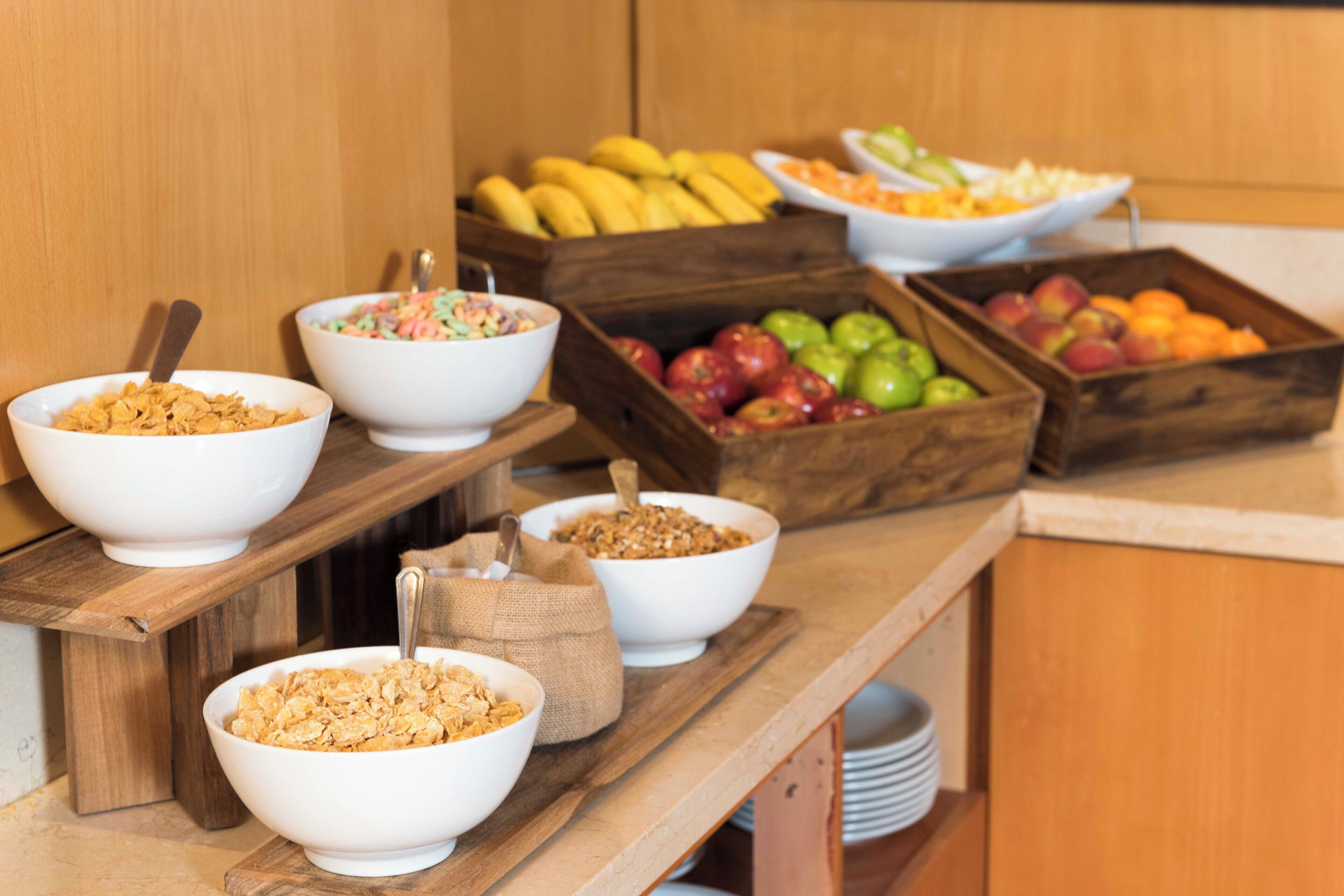 Montaje de buffet con diferentes alimentos, como cereales, frutas y una ensalada.