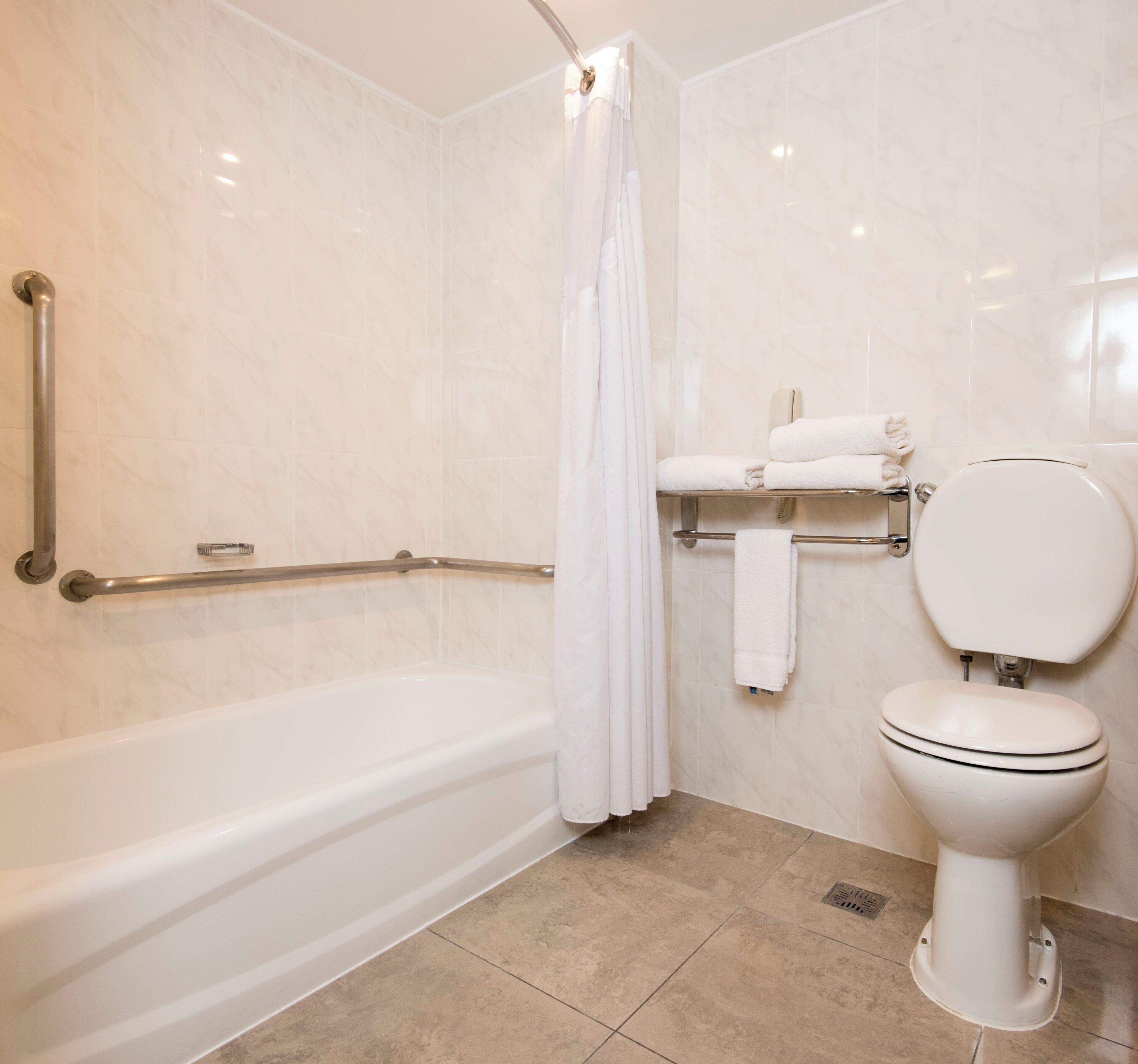 Een badkamer met een bad, toilet en douchegordijn.
