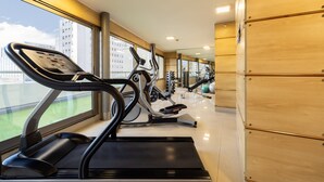 Un gimnasio con cintas de correr, bicicletas estáticas y máquinas de pesas.