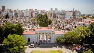 A large, white building with columns and a red roof, surrounded by a densely packed cemetery.