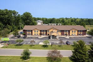 A multi-story hotel with a central entrance, parking lot, and surrounding greenery.