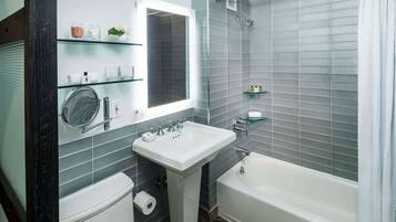 Et moderne badeværelse med et håndvaskarrangement, toilet, badekar og en brusekabine i glas.