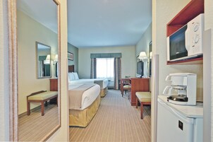 Una habitación de hotel con dos camas, un escritorio, una silla, un televisor y una cafetera.