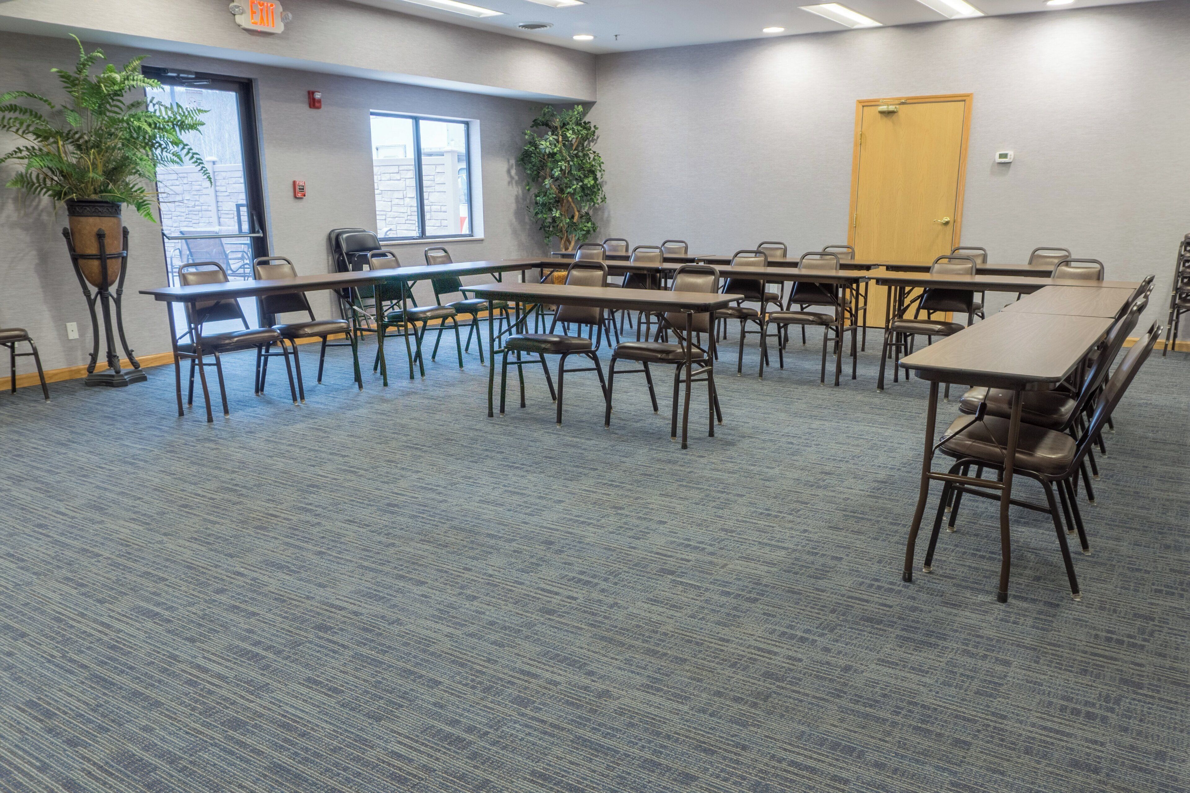 A conference room with a long table, multiple chairs, and potted plants.