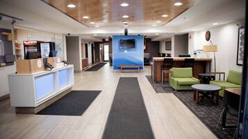 A hotel lobby with a reception desk, seating area, and a TV mounted on the wall.