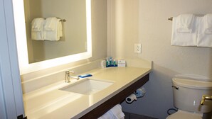 A bathroom with a sink, mirror, and toilet. There are towels hanging on the wall and a sign on the counter. - Holiday Inn Express Winfield by IHG (Hurricane)