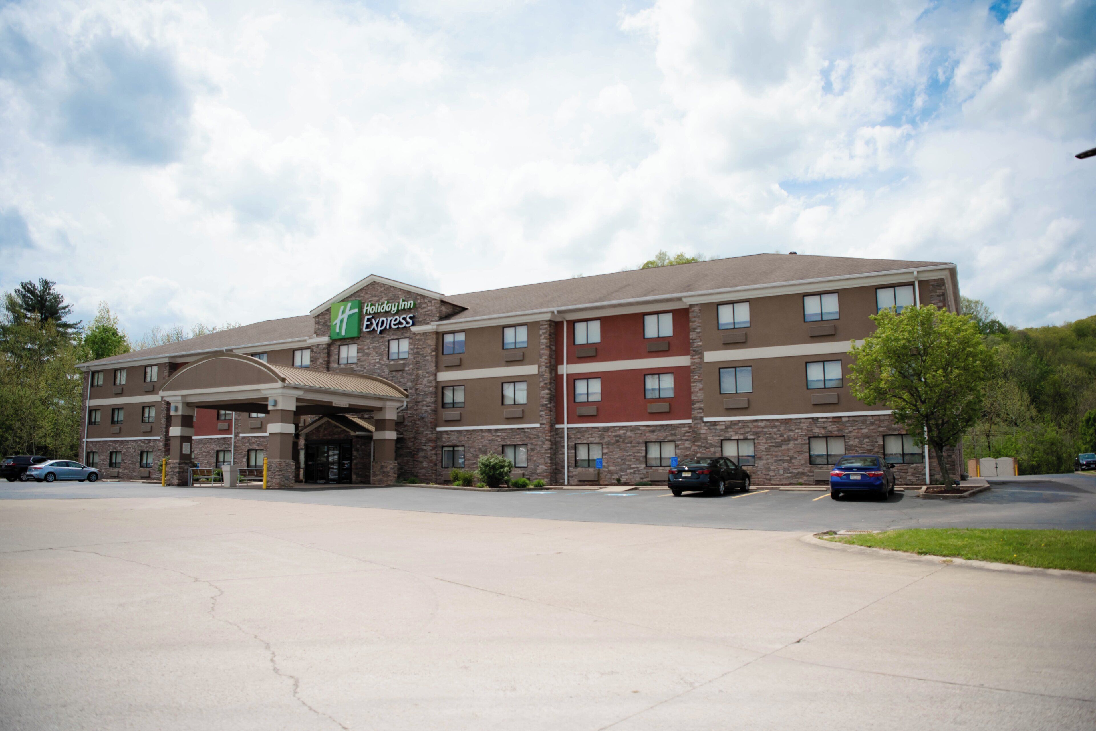 Un hotel Holiday Inn Express con entrada principal, varios pisos y estacionamiento.