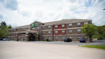 Un hotel Holiday Inn Express con entrada principal, varios pisos y estacionamiento.