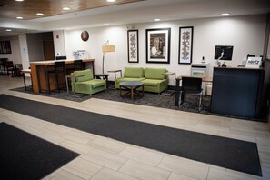 A hotel lobby with a reception desk, green sofas, a coffee table, and a small dining area. - Holiday Inn Express Winfield by IHG (Hurricane)