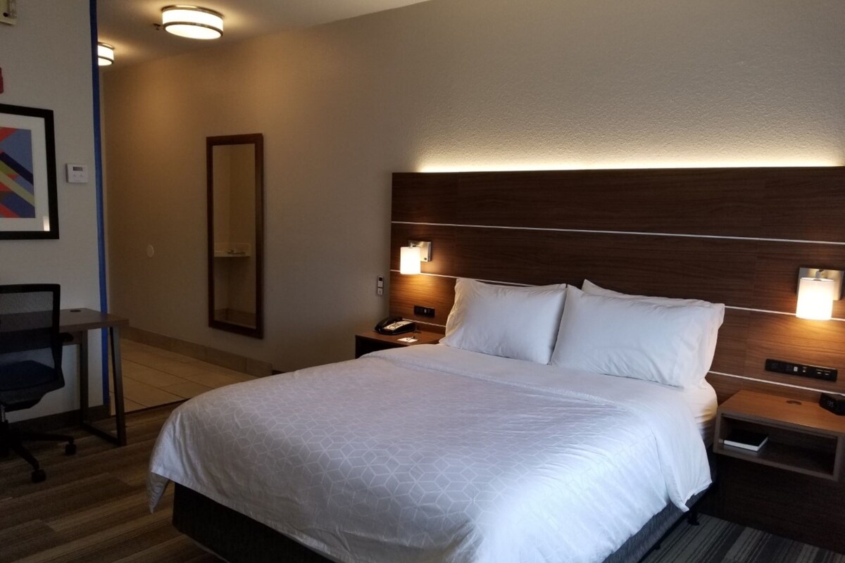 A hotel room with a large bed, bedside tables, a desk, and a chair.