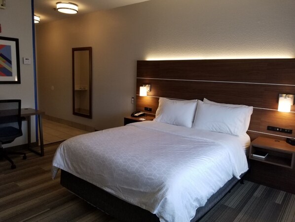 A hotel room with a large bed, bedside tables, a desk, and a chair. - Holiday Inn Express Winfield by IHG (Hurricane)