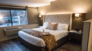 Een hotelkamer met een bed, nachtkastjes, een raam en een wandheater.