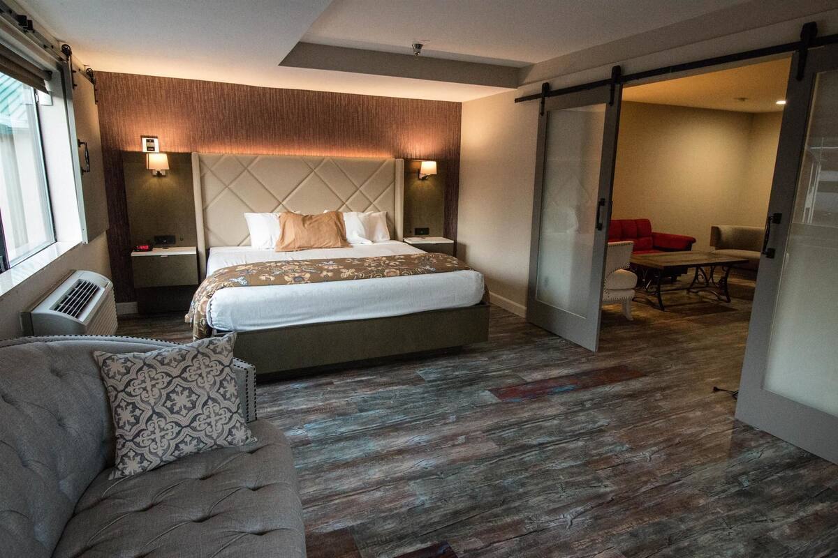 Une chambre d’hôtel moderne dotée d’un grand lit, d’un canapé, d’un coin repas et d’une porte coulissante donnant sur une autre pièce.