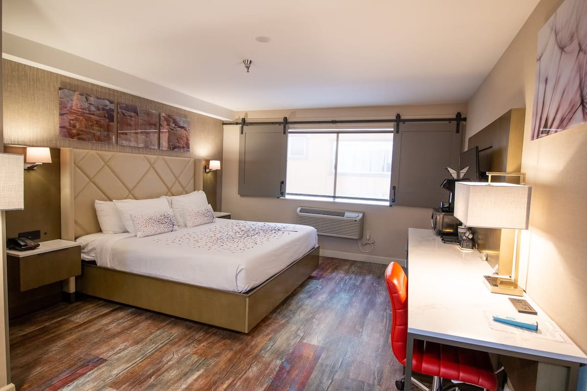 Une chambre d’hôtel avec un lit, un bureau, une chaise et une fenêtre.