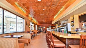 Een restaurantinterieur met zitjes, een bar en een keuken, met grote ramen.