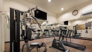 A gym with various exercise equipment, a large mirror, and a clock on the wall. - Comfort Inn & Suites Fenton (Fenton)