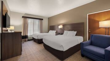 A hotel room with two beds, a desk, a chair, and a television.