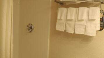 A bathroom with a bathtub, a toilet, and a towel rack with folded towels.