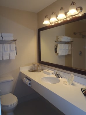 A bathroom with a white sink, a mirror, and a towel rack with folded towels.