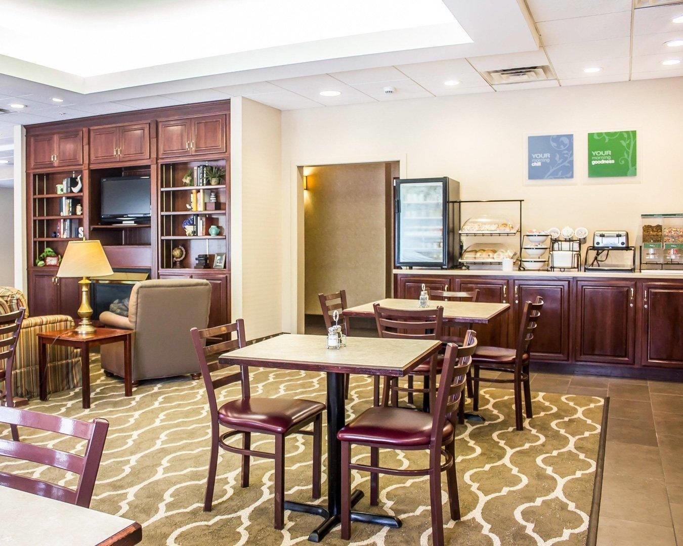 Comedor de hotel con mesas, sillas, televisor y una barra de buffet.