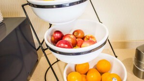 A three-tiered fruit bowl stand with bananas, apples, and oranges.