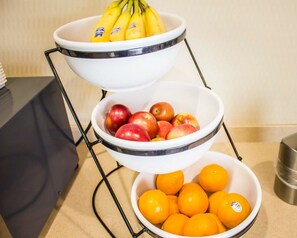 A three-tiered fruit bowl stand with bananas, apples, and oranges.