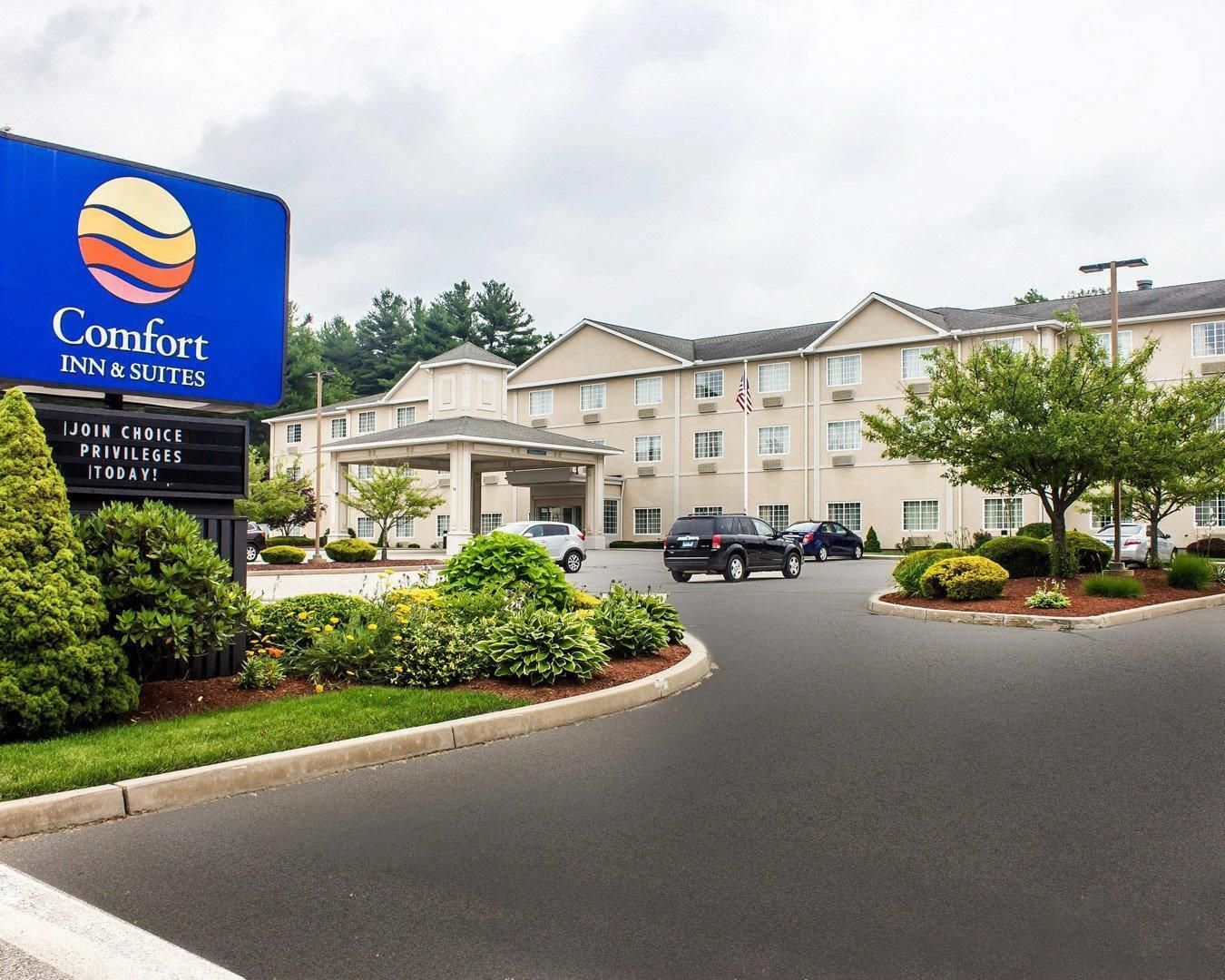 A Comfort Inn & Suites hotel with a large sign, a covered entrance, and a parking lot with several cars.