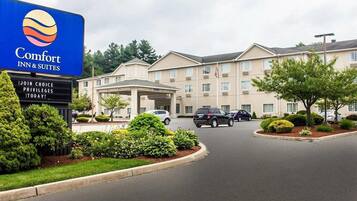 A Comfort Inn & Suites hotel with a large sign, a covered entrance, and a parking lot with several cars.
