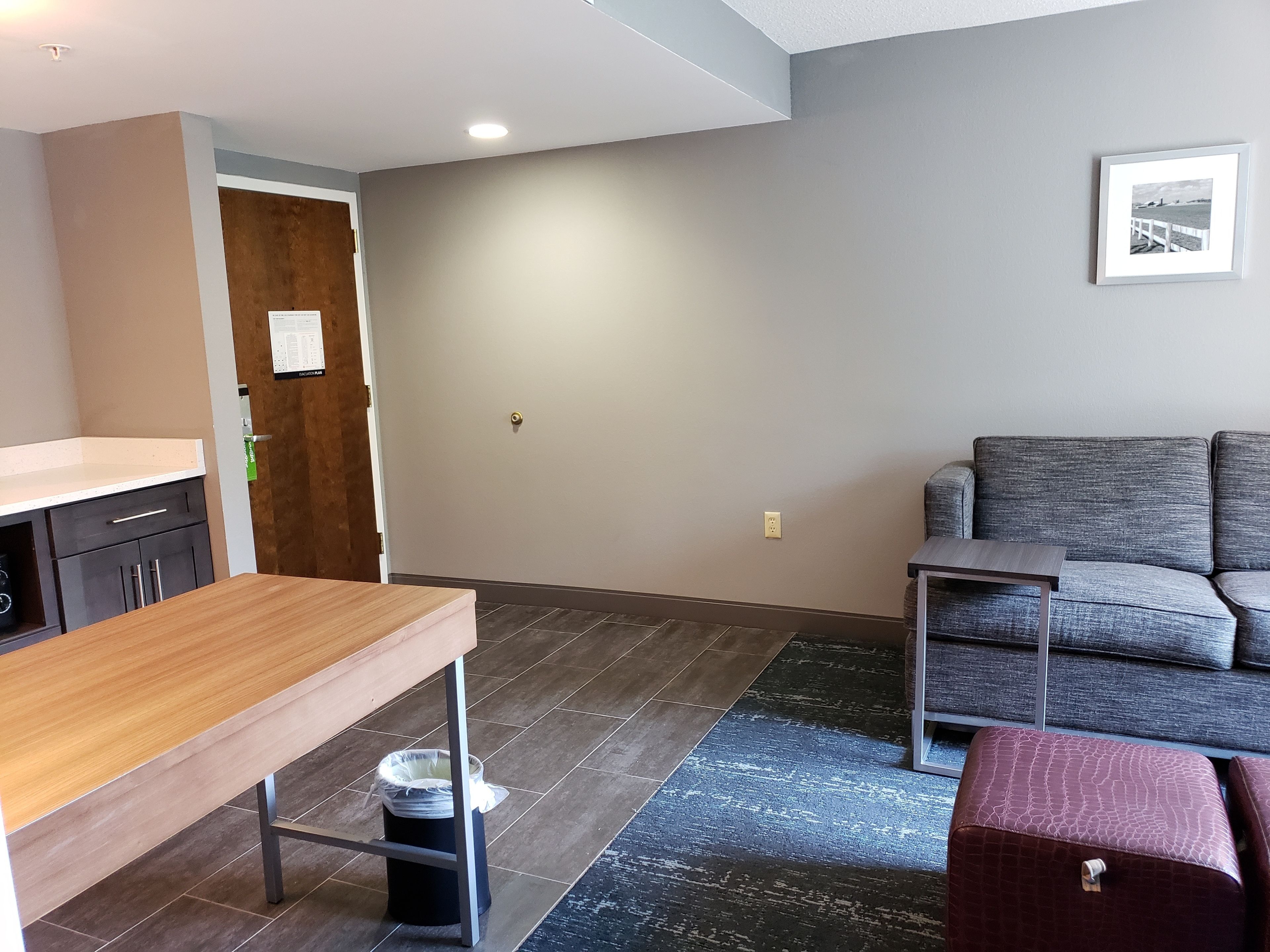 A modern living room with a grey sofa, a wooden table, and a small side table.