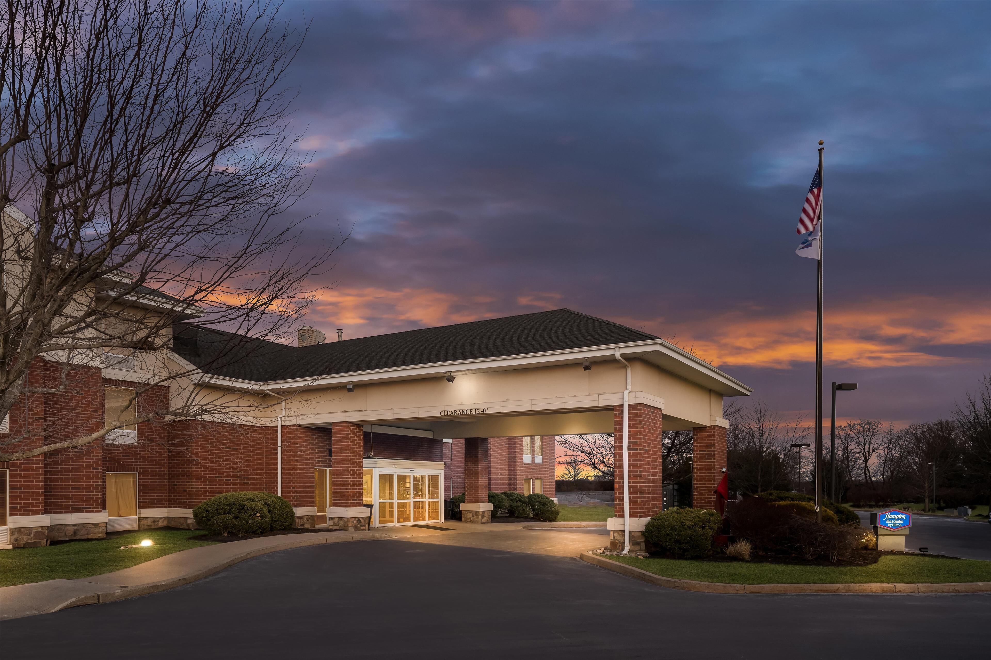 A brick building with a covered entrance, a flag, and a sign indicating a clearance of 12'-0".