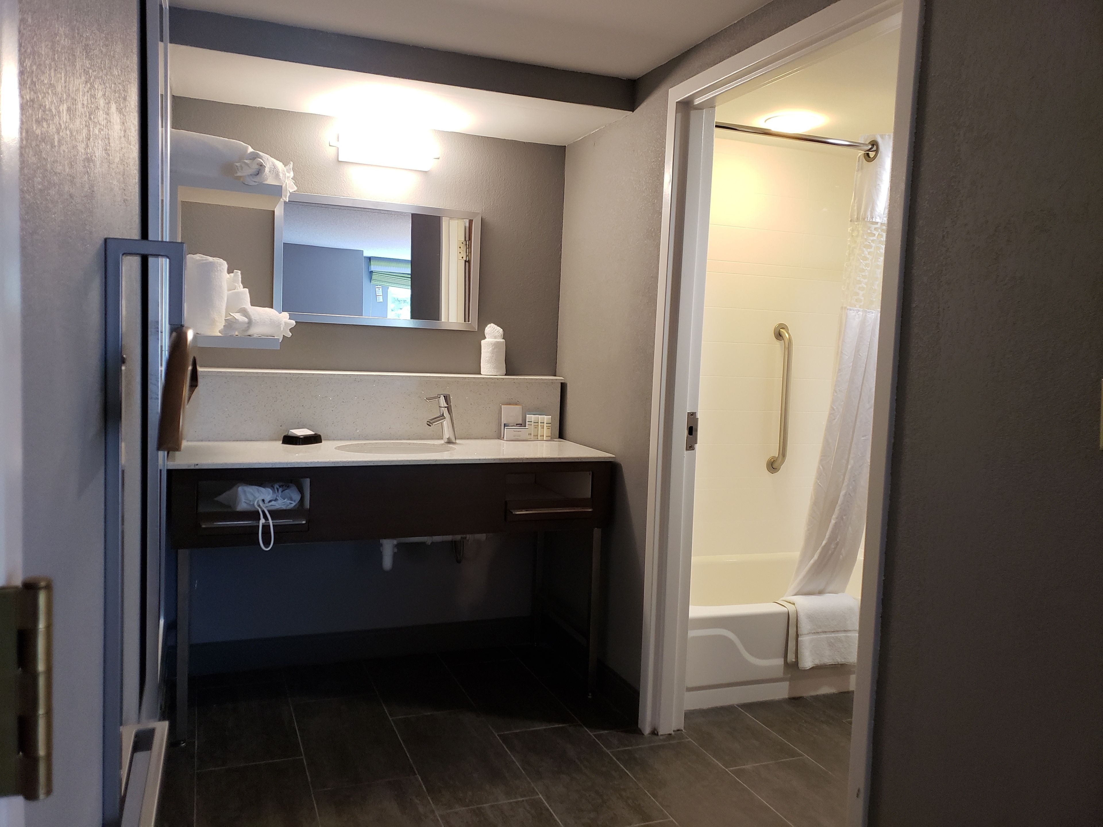 A bathroom with a sink, mirror, towel rack, and a shower with a glass door.