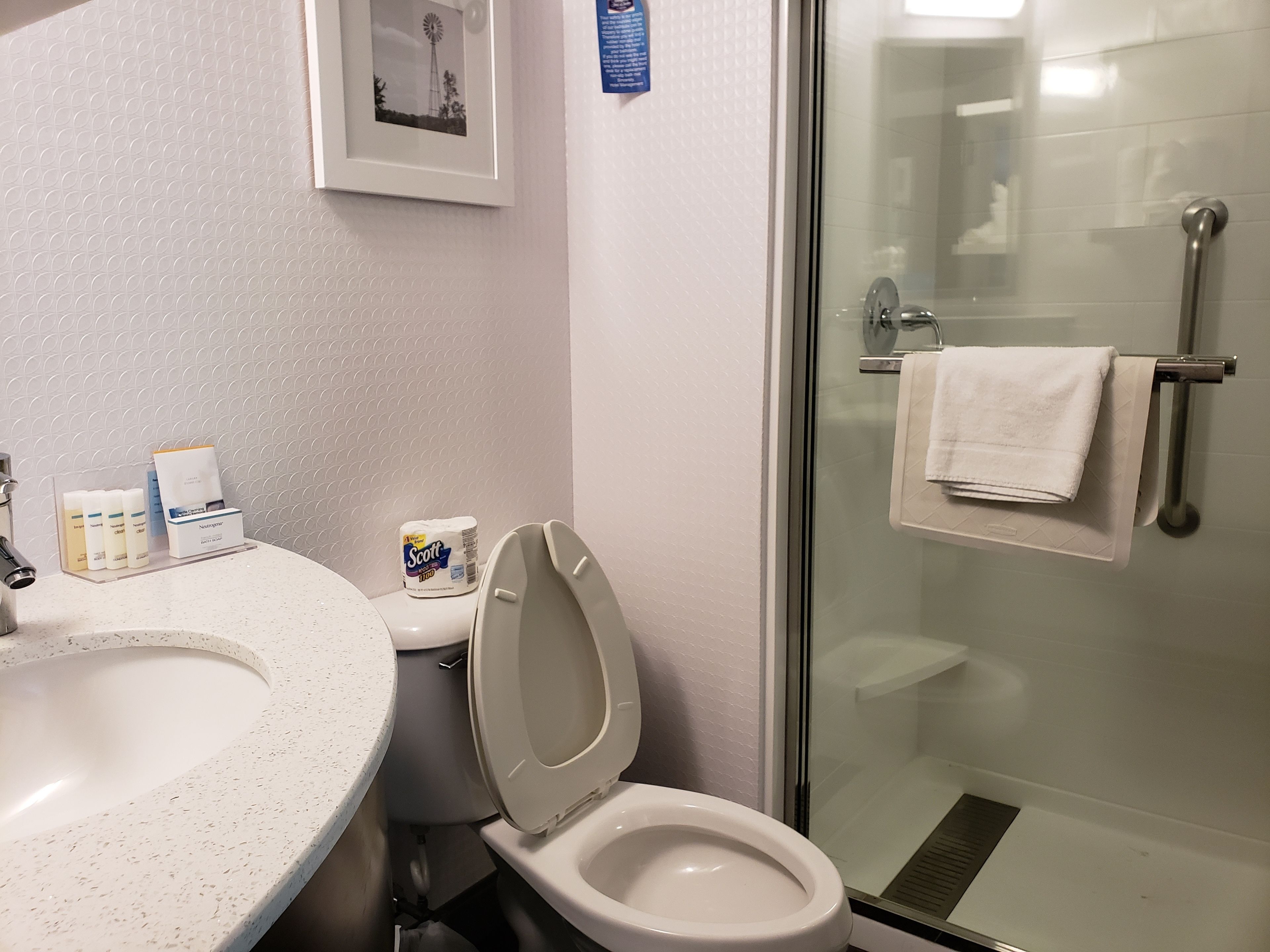 Un baño con inodoro, lavamanos y cabina de ducha de vidrio.
