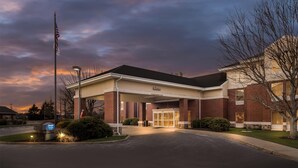 A hotel entrance with a 'Welcome' sign, a flag, and a clear sky. - Hampton Inn & Suites Newtown (Morrisville)