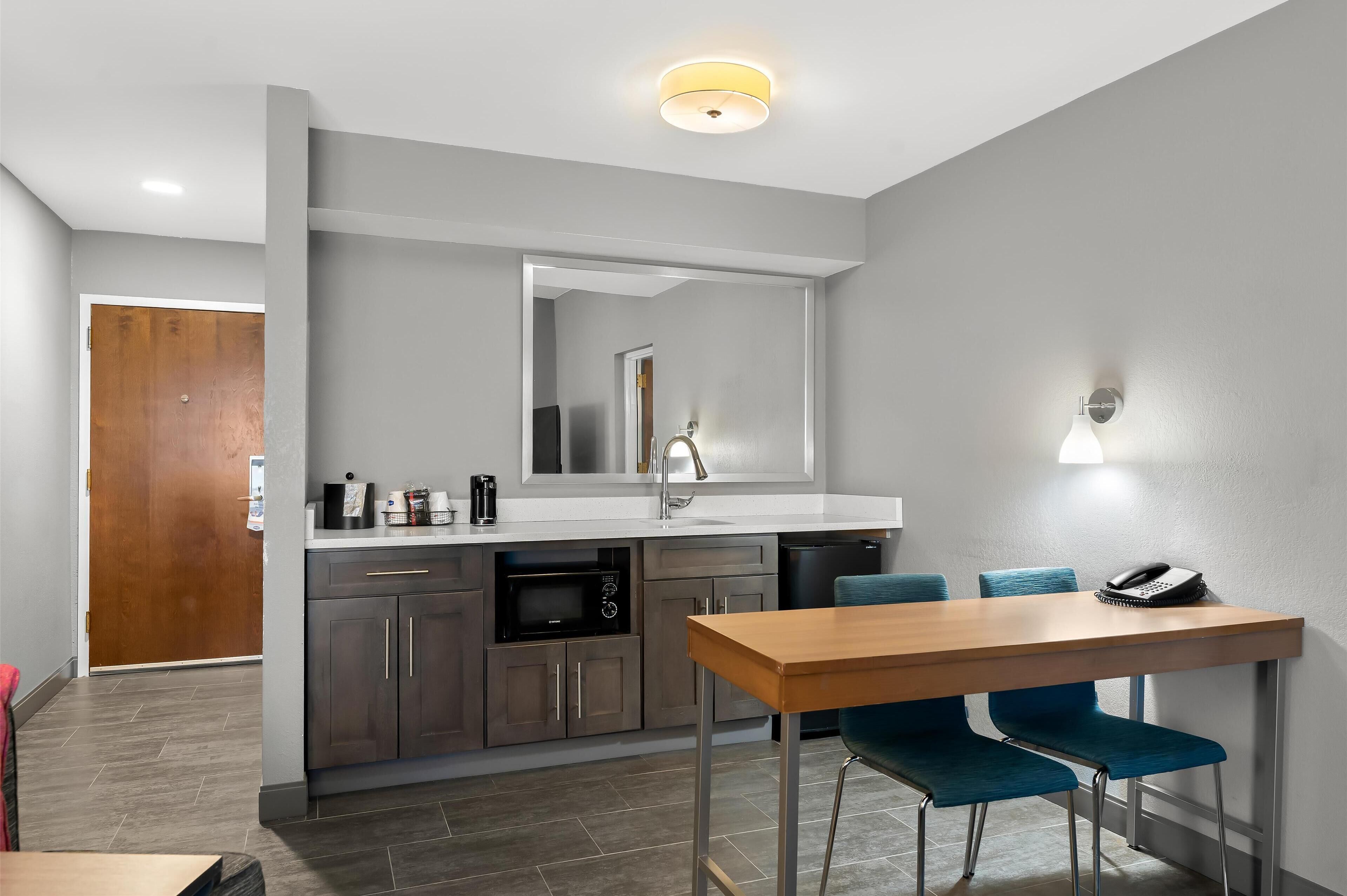 A modern kitchen with grey cabinets, a wooden dining table, and blue chairs.