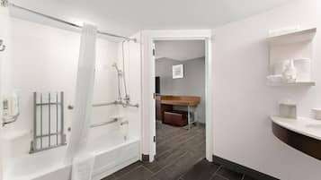 Une salle de bain moderne équipée d’une baignoire, d’une douche et de toilettes. On y trouve un porte-serviettes et une étagère avec des articles de toilette.