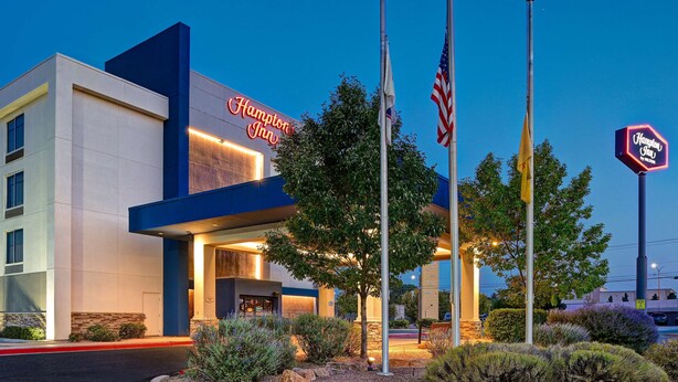 Un hôtel Hampton Inn doté d’une façade moderne, d’une entrée bien éclairée et d’un parterre aménagé devant l’entrée, avec un mât pour drapeau.